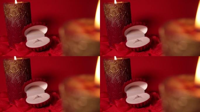 红色天鹅绒外壳的漂亮戒指。玫瑰花瓣，背景，蜡烛。文字、2月14日、情人节的空白。订婚，结婚婚礼