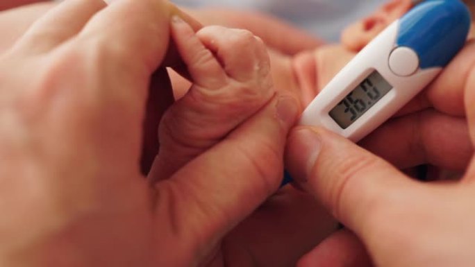 母亲或父亲用数字温度计测量婴儿温度。这个孩子几个月大。婴儿体温正常。