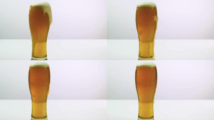 啤酒泡沫从一杯啤酒中流下，啤酒在白色背景上。