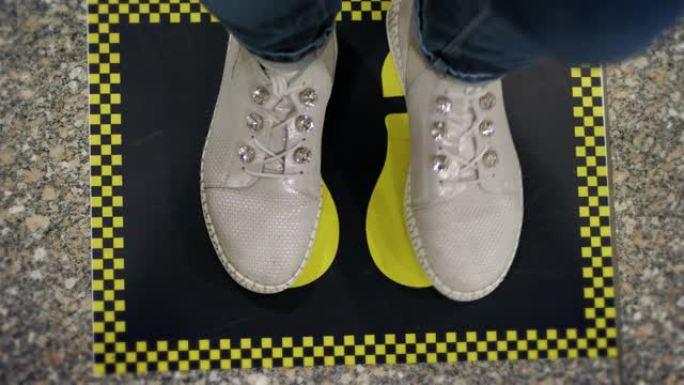 足迹标志。社交距离。地板上的黄色标记，以在冠状病毒流行期间保持人与人之间的社交距离。特写。在机场。新