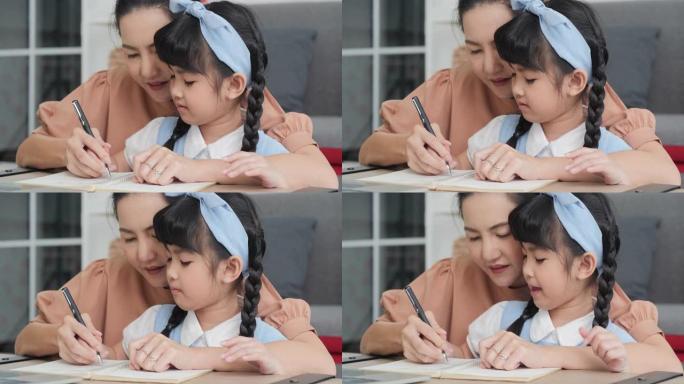 亚洲妈妈牵着女儿的手写书学习。用心学习。