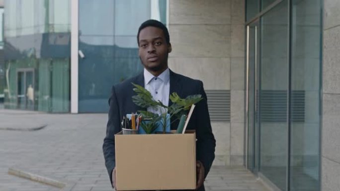 冠状病毒和失业。悲伤的非裔美国人经理沿着办公室去户外，拿着一箱私人员工