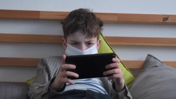 检疫冠状病毒新型冠状病毒肺炎期间，男孩脸上戴着医用口罩，病毒情绪激动地在智能手机上玩游戏，紧张地把手