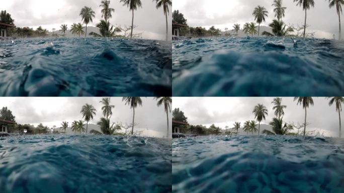 糟糕的假期概念。大雨落入海洋附近的豪华游泳池，背景是椰树。