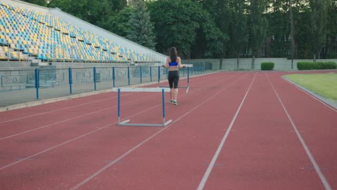 跨栏训练。年轻女运动员在田径比赛中练习障碍