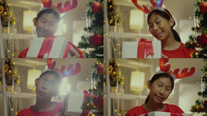 快乐的亚洲女孩穿着红色毛衣摇晃礼品盒后收到家人送的圣诞装饰品在家，生活理念。