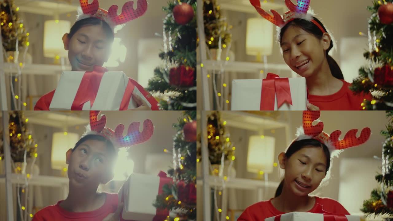 快乐的亚洲女孩穿着红色毛衣摇晃礼品盒后收到家人送的圣诞装饰品在家，生活理念。