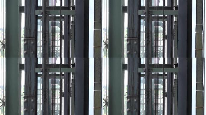 玻璃电梯钢绳特写。焦点在远处，前景模糊。