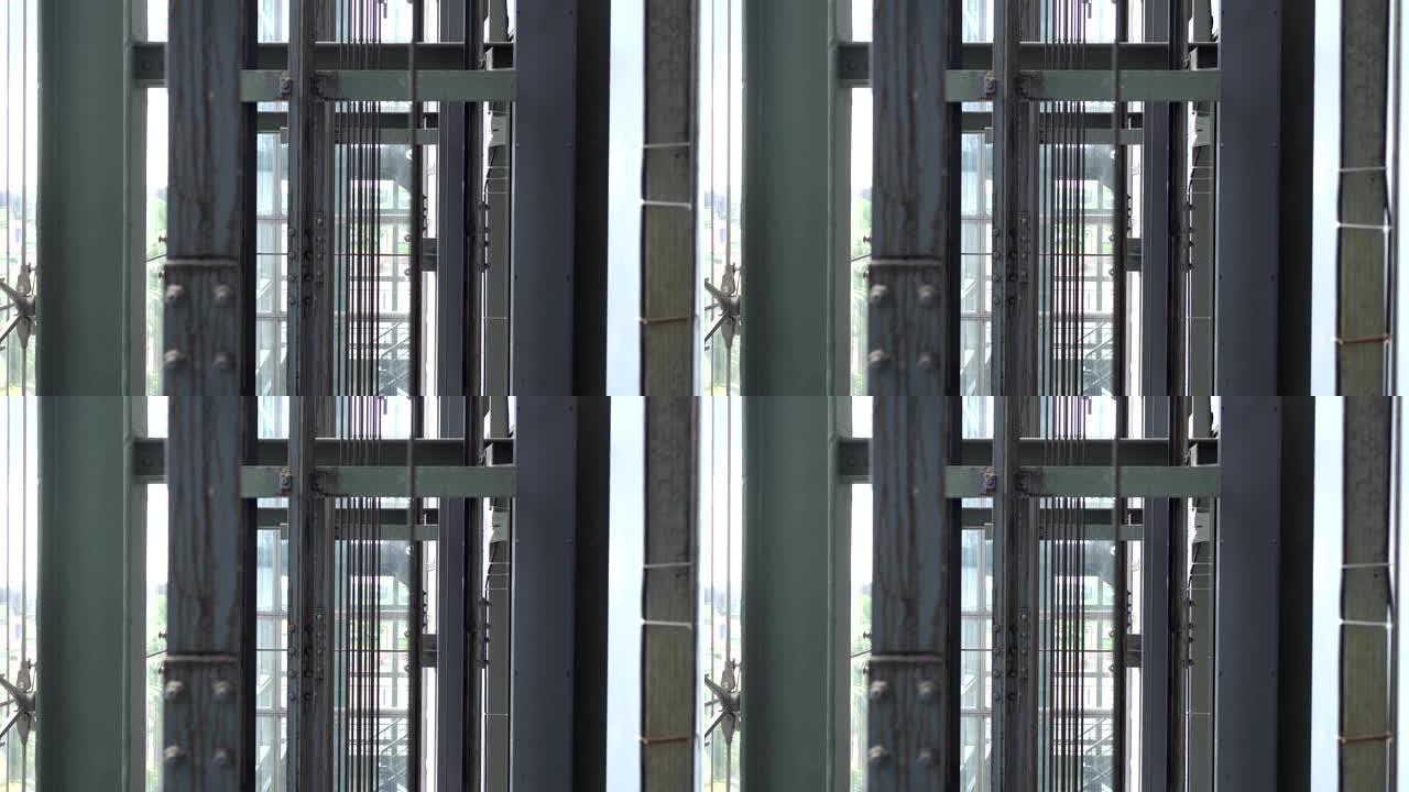 玻璃电梯钢绳特写。焦点在远处，前景模糊。