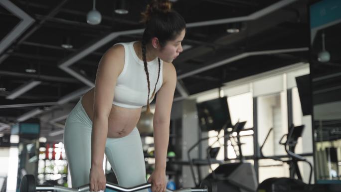 现代女性怀孕的妇女在健身房锻炼身体撸铁