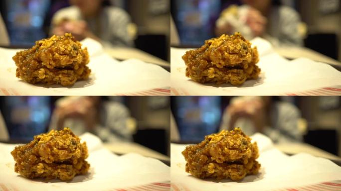 一个小孩在快餐店吃炸鸡。焦点在前面左边的炸鸡，背景模糊。