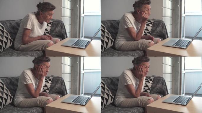 老年妇女与家人进行视频通话，微笑着挥手。头发花白的高级女性在家使用笔记本电脑进行视频通话。新型冠状病