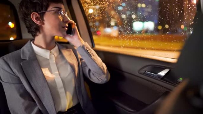 年轻的女商人在电话上聊天，同时从车窗看城市
