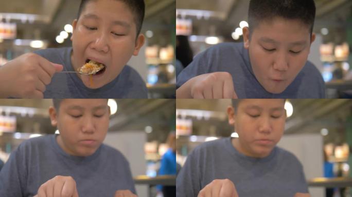 亚洲青春期男孩在美食广场吃食物，生活方式概念。
