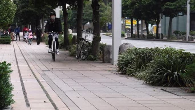带着黑色背包和防护面具的年轻人快递员在街上骑着自行车穿过城市，运送食物。戴防护头盔的人。送餐概念。