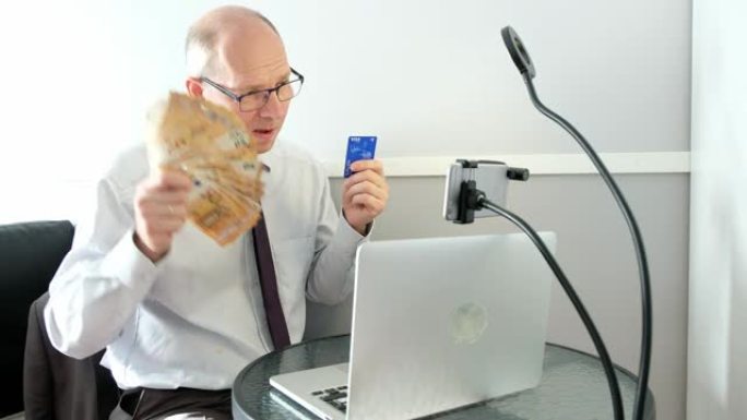 电脑前的白人。男子在电脑屏幕前挥舞着一捆信贷钱