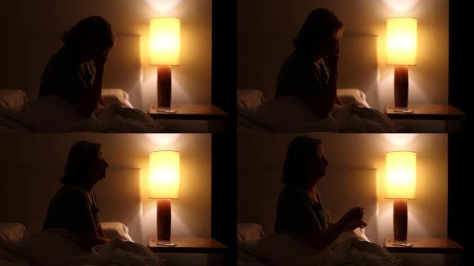 焦虑的女人坐在床边无法入睡。夜不能寐的人在担心