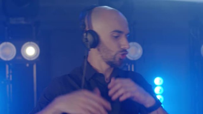 带耳机的精力充沛的秃头男子的现场DJ表演，在派对音乐会音乐家舞台上跳舞