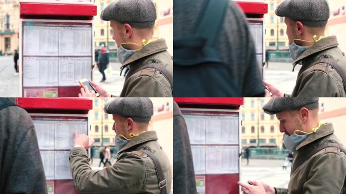 一名男子在城市的公交车站查看公共交通时间表。