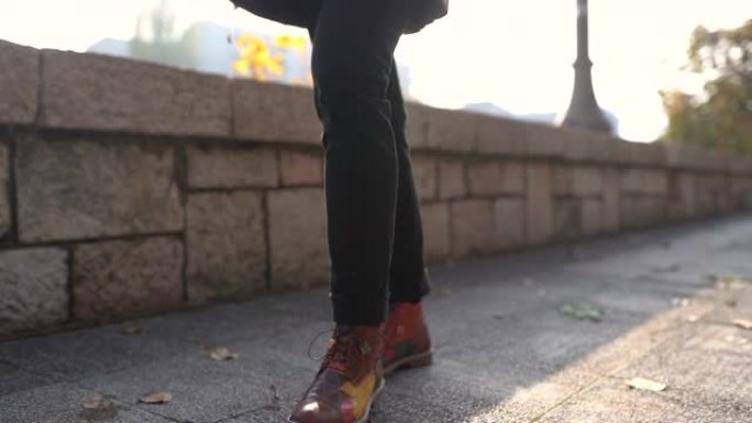 在阳光明媚的秋天，穿着名牌鞋的男人在城市行走