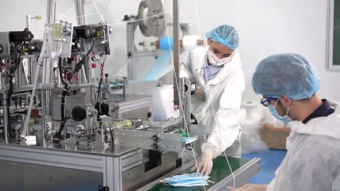 口罩工厂的工人正在使用机器在病毒爆发和粉尘污染pm2.5期间生产所需的口罩。口罩厂的工人正在检查产品