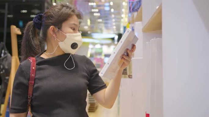 covid疫情后新常态年轻聪明的亚洲女性购物新的生活方式在超市用脸或口罩保护手选择消费品新的正常生活