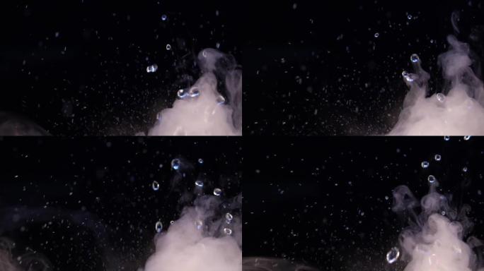 放松视频，在黑色背景上有飞溅和水滴，有雾或烟，具有循环功能。close-up.Swirl中的水飞溅和