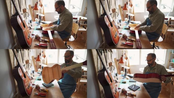 乐器制造商坐在工作台上，在他的车间里建造吉他