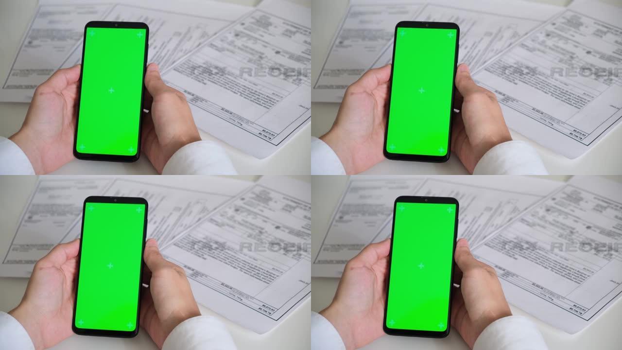 电话与绿屏和付款收据，税务文件在白色背景顶视图。智能手机chromakey向不同方向滑动。复制空间