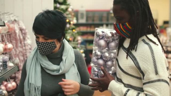 蒙面的跨种族夫妇正在流行的商店里选择圣诞装饰品。
