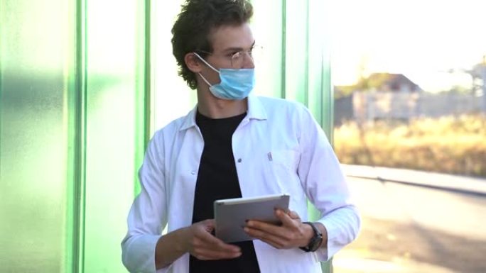 年轻的男性医生戴着口罩，使用数字平板电脑，在新型冠状病毒肺炎爆发期间指向或显示城市的方向。高质量4k