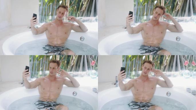 帅气的肌肉男在洗澡，在手机上自拍，微笑，眨眼
