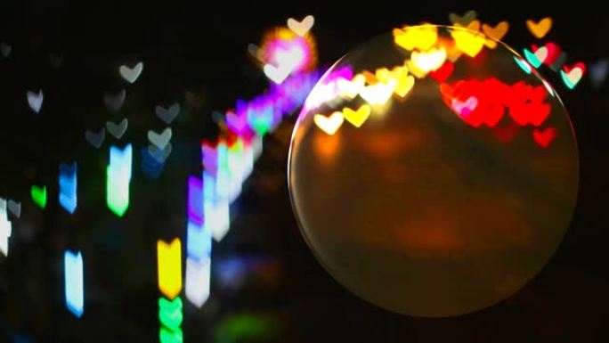 玻璃地板上的水晶球和来自街道的心形彩虹灯反射在球面上
