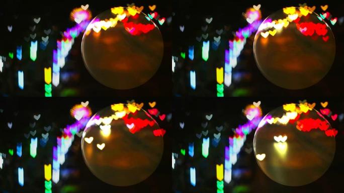 玻璃地板上的水晶球和来自街道的心形彩虹灯反射在球面上