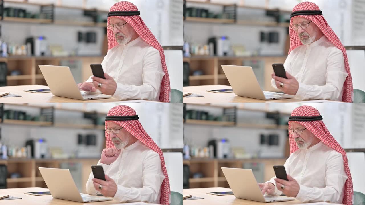 在笔记本电脑和智能手机上工作的阿拉伯老商人