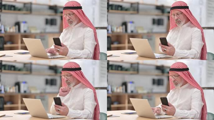 在笔记本电脑和智能手机上工作的阿拉伯老商人