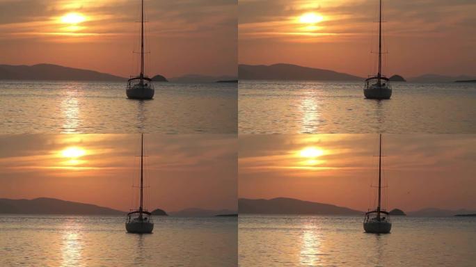 日落时独自帆船。橙色阳光的大气海景。