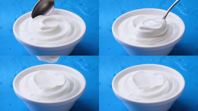 一碗蓝色背景的酸奶油，希腊酸奶