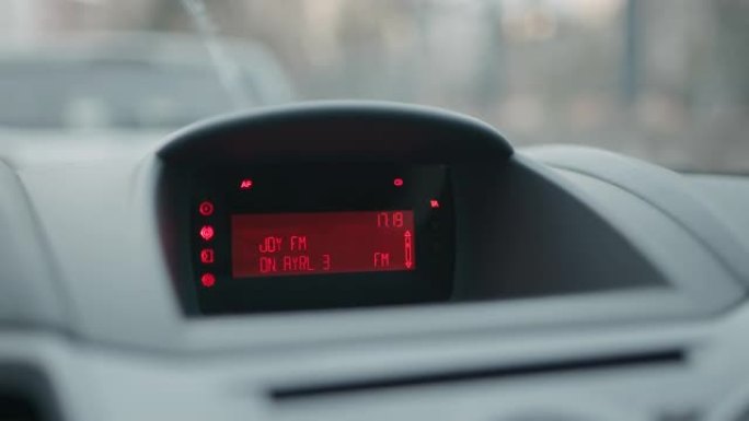 汽车仪表板和红色液晶显示屏，显示时钟并在slowmo中搜索调频广播电台频道
