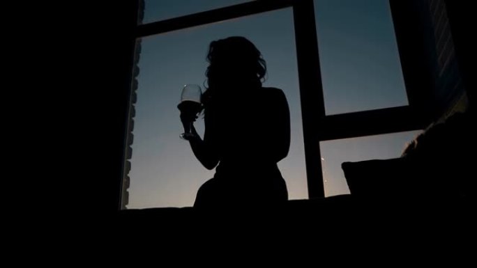 窗台玻璃上摇晃葡萄酒的女孩剪影