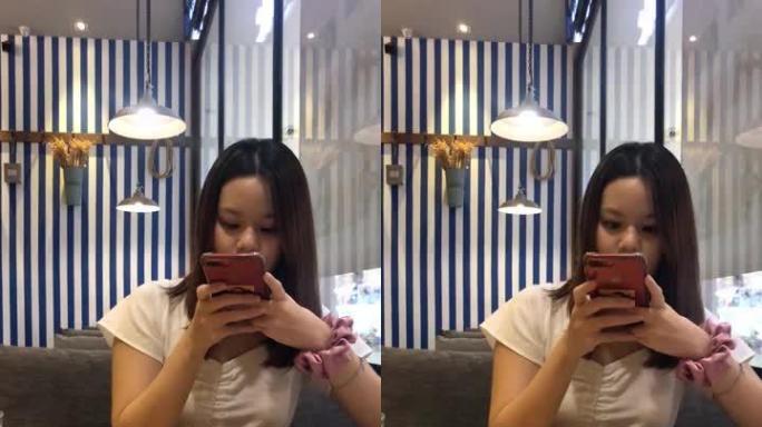 亚洲少女在餐厅吃饭时使用智能手机网络摄像头，智能手机垂直格式视频