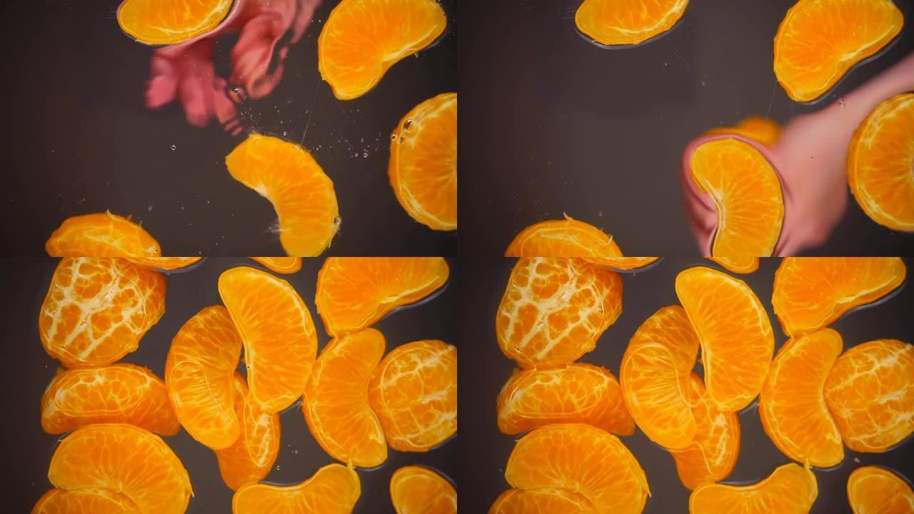 去皮的橘子切片掉入玻璃表面的水中。底视图。