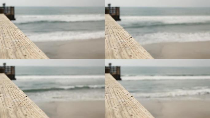 木墩栏杆，海滨木板路，美国加利福尼亚海滩。散焦的海洋，海浪。
