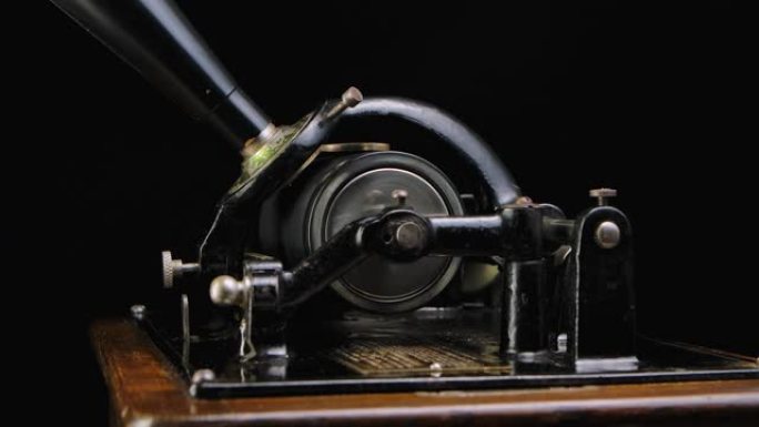 微距详细拍摄经典爱迪生留声机在黑色工作室背景下播放音乐。复古复古机器重现听音乐的声音。侧视图。特写。