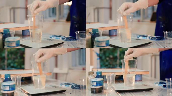 在玻璃秤中混合透明液体。油漆前准备环氧材料。