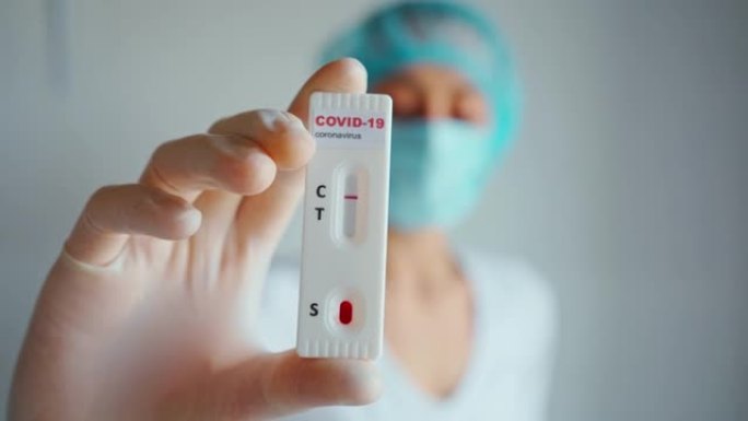 医生或护士在防护面罩和手套手持实验室卡试剂盒测试病毒性疾病新型冠状病毒肺炎