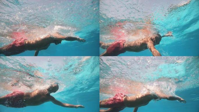 男子在游泳池里游泳爬行。水下慢动作视图