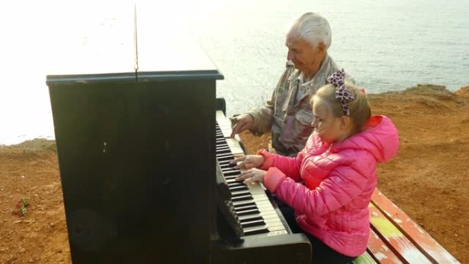 老人和小女孩在海边一起弹钢琴
