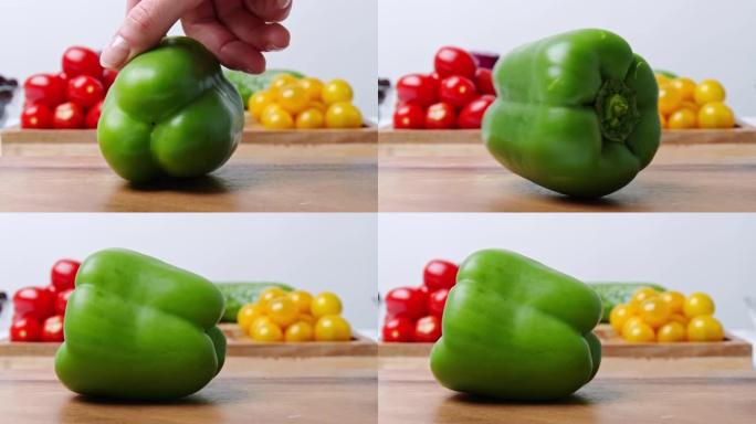 女人的手以慢动作在砧板上旋转绿色甜椒的特写镜头，背景为4K，背景为蔬菜。