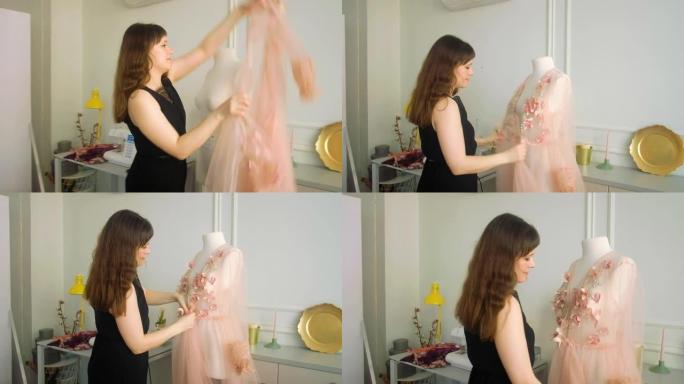 女设计师在她明亮的工作室里穿着粉色透明连衣裙